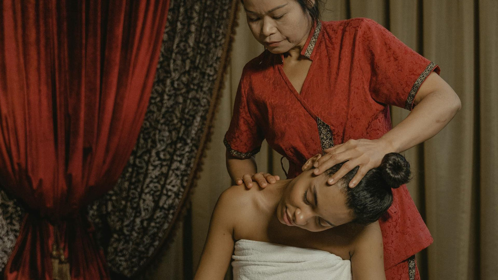 Massage thaï traditionnel : une masseuse masse la nuque d'une femme