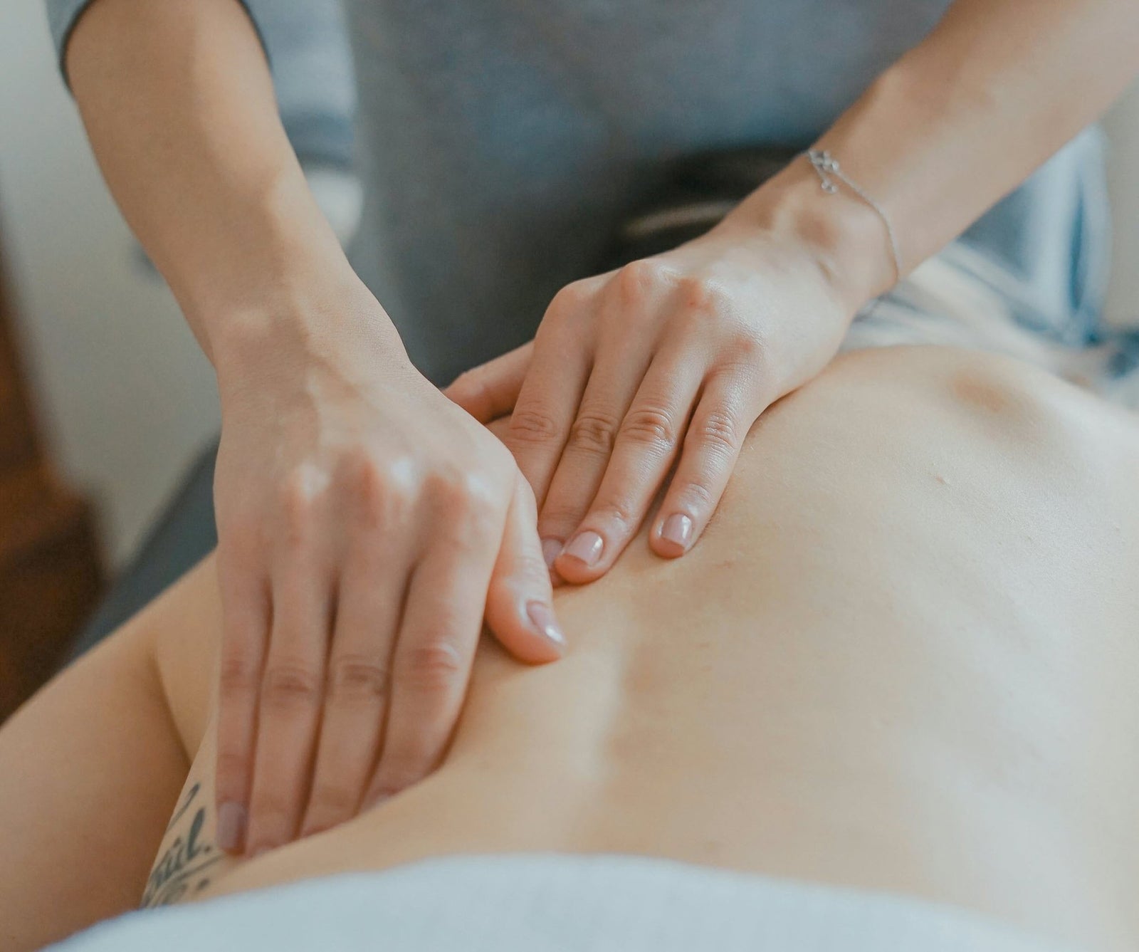 Une femme qui se fait masser le dos, allongée sur le ventre sur une table de massage