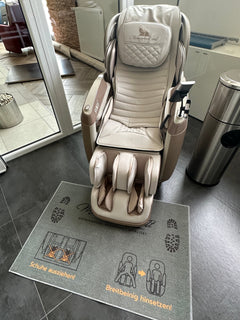 
Hinweis-Fußteppich „Schuhe ausziehen“ vor einem Massagesessel